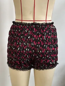 Dettaglio ravvicinato di pantaloncini neri smocked con stampa ciliegie e rifinitura in pizzo.