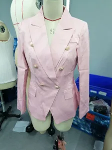 Detalle de chaqueta rosa de doble botonadura con botones dorados grabados y solapa.
