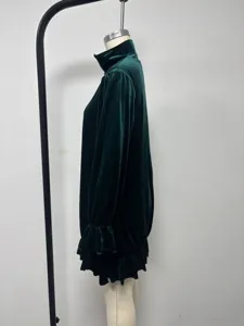 Side view of the dark green velvet long sleeve dress with stand collar and ruffles.
