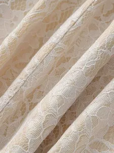 Close-up detail of elegant beige and white floral lace fabric for women apparel styling.