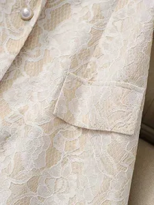 Detailed view of the elegant beige lace vest, highlighting fine floral lace texture and pearl button.