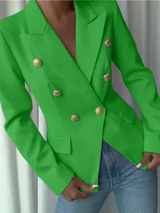 Detalle de una chaqueta cruzada verde con botones dorados en relieve y corte entallado.