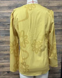 Detail shot of back floral embossed yellow long sleeve top, stylish texture close up view.