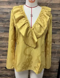 Yellow V-neck long sleeve top detail showing exquisite floral embossed pattern and ruffles.