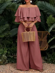 Elegantes schulterfreies Rüschen-Crop-Top und hochtaillierte weite Hosen im Set für den Urlaub.