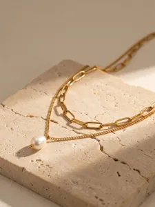 Gros plan d'un collier double en acier inoxydable avec un pendentif en perle d'eau douce.