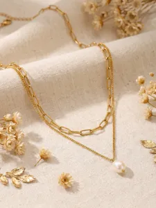 Gros plan détail du magnifique collier double couche avec pendentif perle et chaîne dorée.