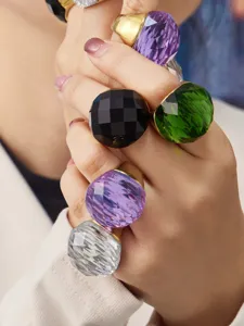 Nahaufnahme farbiger, großer facettierter Glasringe, auffälliger vergoldeter Edelschmuck.