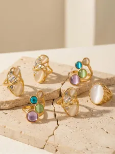 Dettaglio del set di anelli in acciaio inossidabile dorato con pietra occhio di gatto multicolore.