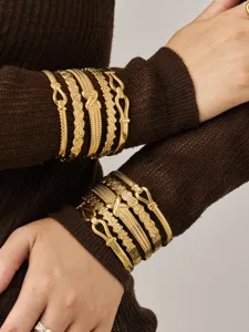 Detailed close-up view of stackable gold-plated stainless steel geometric textured bangles.