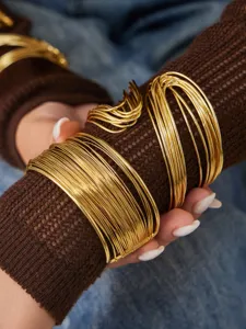 Gros plan de jonc en fil doré à enroulement multicouche, bijoux de main élégants et empilables.