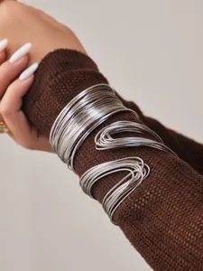 Gros plan détaillé d'un bracelet manchette en fil multicouche sur manche en tricot.