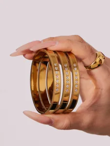 Detail shot of three gold-plated stainless steel fashion bangles with sparkling cubic zirconia stones.