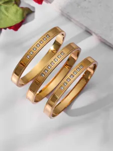Detailed shot of three stylish gold-plated stainless steel crystal bangles with zirconia.
