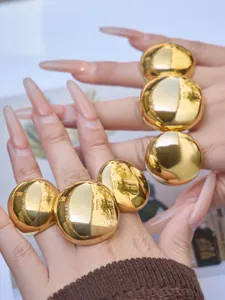 Oversized gold ball geometric rings detail view, exaggerated polished wide statement fashion jewelry.
