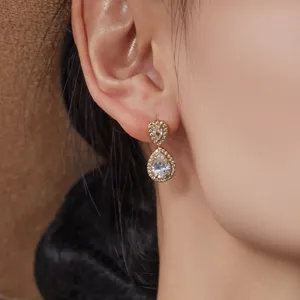 Elegantes pendientes colgantes chapados en oro con brillantes circonitas en forma de pera.