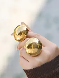 Close-up of oversized gold dome rings featuring a glossy mirror finish, perfect detail shot.