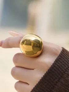 Close-up of a chic gold-plated sphere geometric ring, featuring a glossy wide surface design.