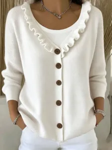 Close-up detail of white knit cardigan showing elegant ruffle collar and brown buttons.