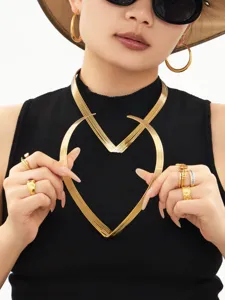 Close-up detailopname van de minimalistische V-vormige hartketting en gouden ringen.