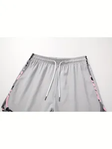 Close-up detail of grey athletic shorts waist with white drawstring and pink side stripe.