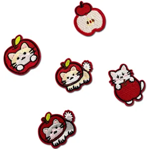 Gros plan détaillé de patchs brodés chat et pomme mignons, accessoire de vêtement en tissu.