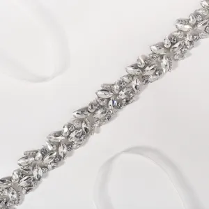 Rhinestone bridal belt detail view, sparkling crystal embellishment on white ribbon sash.