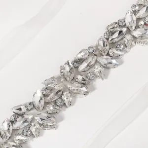 Detailed closeup of sparkling rhinestone bridal belt with clear crystal stones on white ribbon.