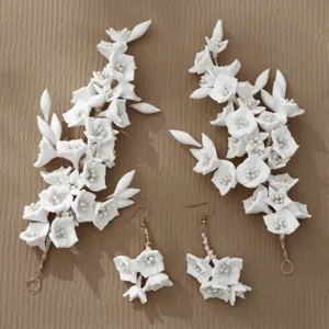 Dettaglio di accessori capelli con fiori di argilla bianca, orecchini sposa floreali