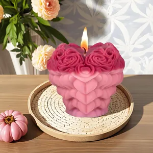 Detail shot of heart-shaped floral scented candle with rose design and warm flame glowing.