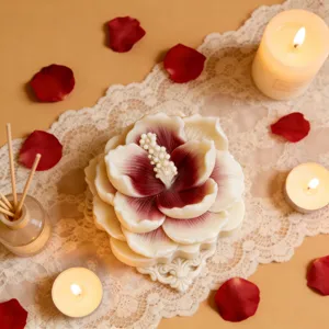 Detailansicht einer handgefertigten Blumenkerze mit Rosenblättern und warmem Kerzenlicht.