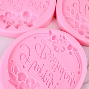 Detalle de molde de silicona rosa redondo con relieve floral y texto de feliz cumpleaños.