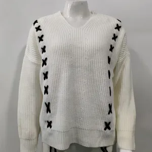 Detail view of the white V-neck knit sweater featuring stylish black cross stitch trim.
