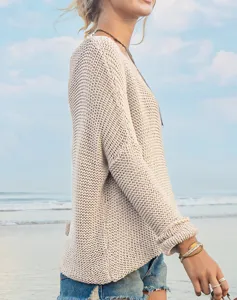 Detailaufnahme eines gemütlichen beigen Strickpullovers am Strand mit langen Ärmeln.