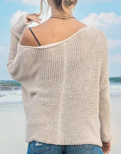 Rückseitiges Detail eines beige, schulterfreien, grobgestrickten Pullovers am Strand.