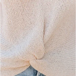 Close-up detail van de beige gebreide top met knoopdesign en zachte textuurkwaliteit.