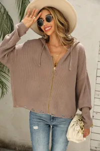 Close-up detail of women's knitted hooded cardigan with distressed hem and front zip closure.