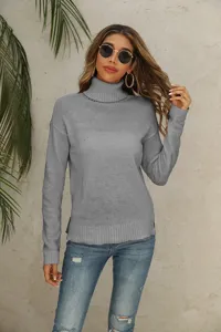 Detailed shot of grey turtleneck knit sweater worn by model with plant backdrop.