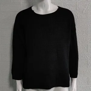 Detaillierte Nahaufnahme des schwarzen Waffelstrick-Pullovers mit Struktur und Ärmeln.