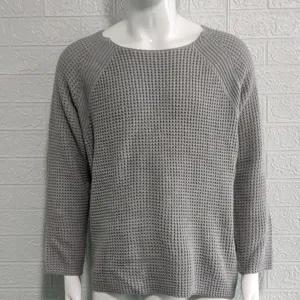 Grauer Waffelstrick Pullover Detail mit strukturierter Stoffoberfläche, langen Ärmeln.