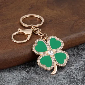 Fashionable gold-plated four-leaf clover keychain with green enamel and sparkling rhinestones.
