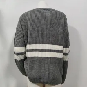 Detail view of women's grey knit sweater featuring classic white horizontal stripes and crew neck.