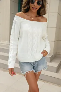 White off-shoulder cable knit sweater detail showing textured fabric and stylish cut.