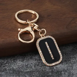 Gold metal rhinestone letter keychain detail, black enamel pendant with sparkling crystals.