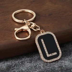 Gold metal initial L keychain with sparkling rhinestones and black enamel pendant accessory.