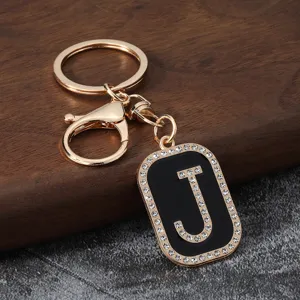 Gold metal letter J rhinestone keychain detail view, stylish bag accessory and key holder.
