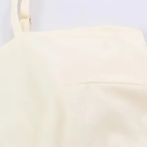 Cream strap dress detail, adjustable shoulder strap, soft fabric texture close-up for women.