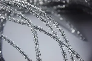 Close-up detail shot of shiny silver tinsel stems, perfect for DIY crafts and Christmas decor.