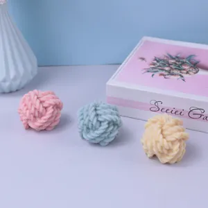 Detailed shot of cute knot yarn ball candles or molds in pink, blue and yellow colors.