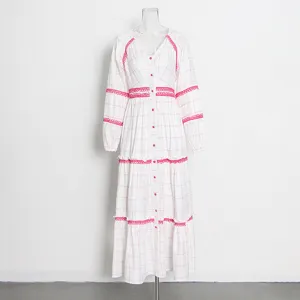 Vista detallada de un vestido blanco de manga larga con estampado de cuadros rosas y encaje.
